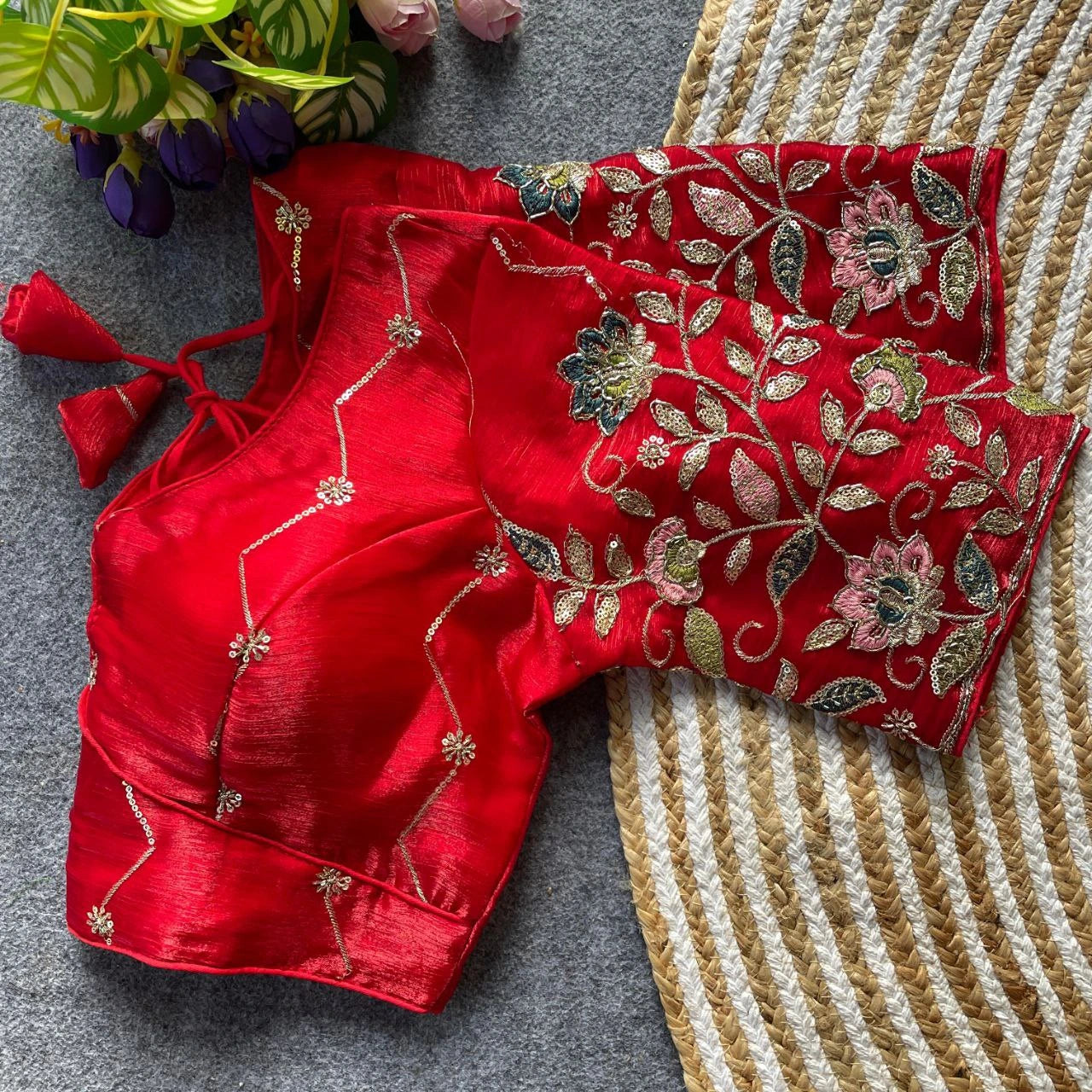 Red embroidered blouse on a textured surface with flowers in the background